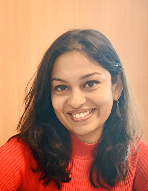 A female researcher in a red sweater smiles at the camera