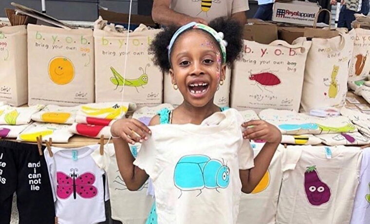 A young girl proudly holds up her Bugged Out t-shirt