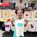 A young girl proudly holds up her Bugged Out t-shirt
